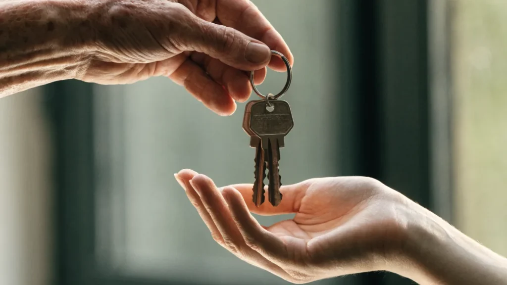 Clés de maison transmises d'une main plus âgée à une main plus jeune